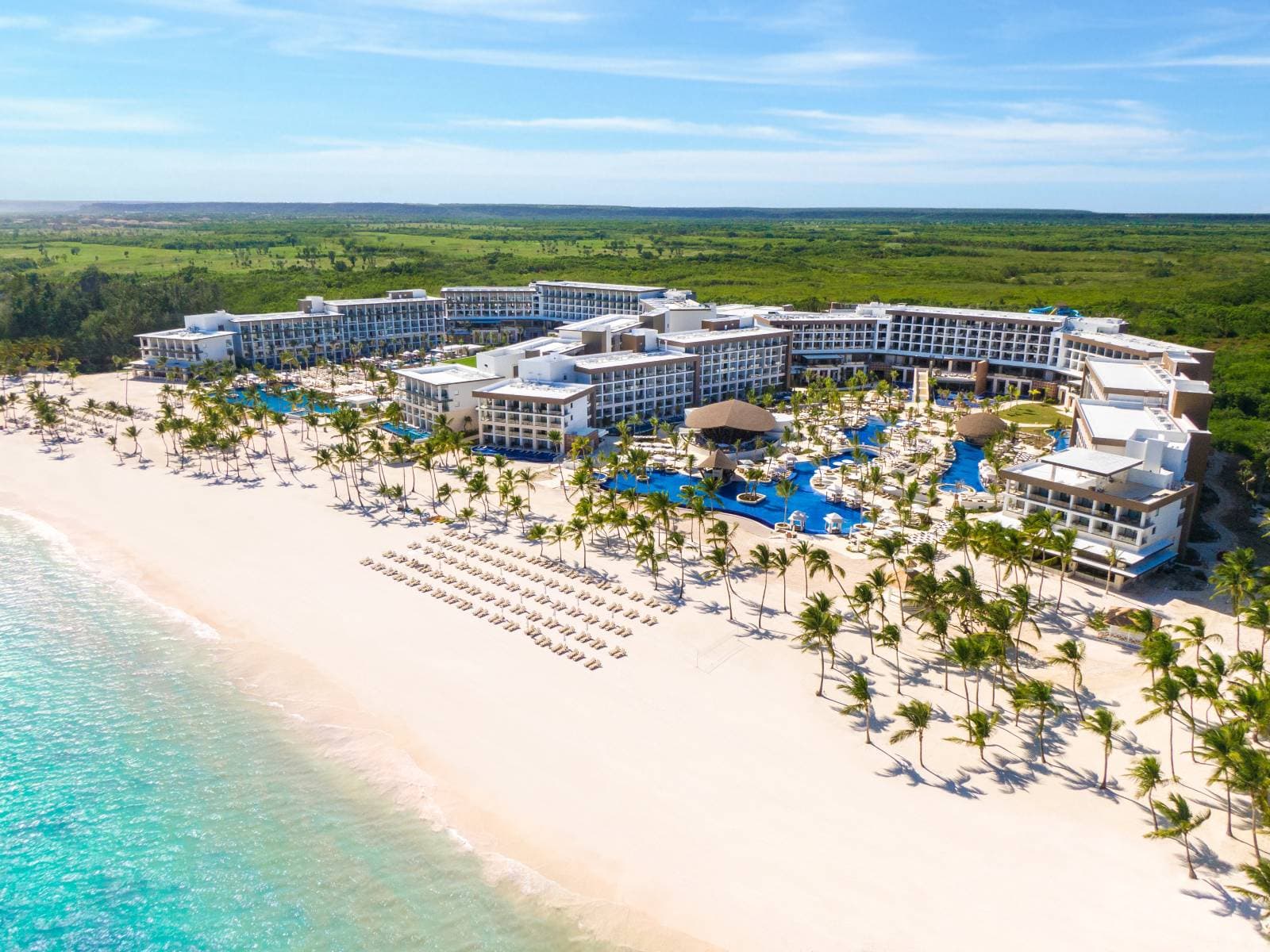 View of the Hyatt Ziva Cap Cana infinity pool merging with the Caribbean Sea, framed by modern architecture.