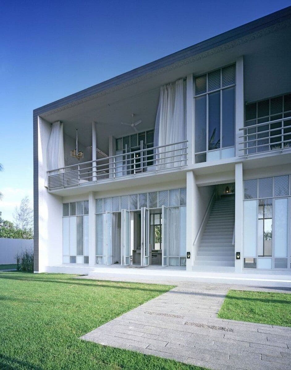 A stark white pool villa at SALA Phuket with sinusoidal walls and a private swimming pool reflecting the blue sky.