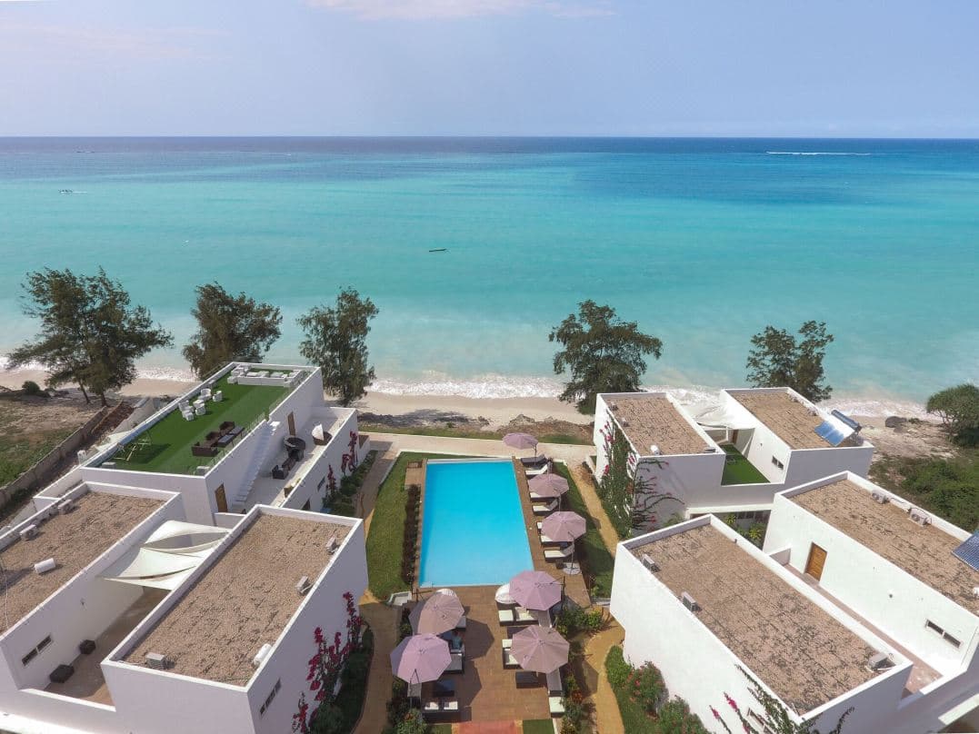 A rim-flow infinity pool at Nungwi Dreams blending seamlessly with the turquoise Indian Ocean under a clear Zanzibar sky.