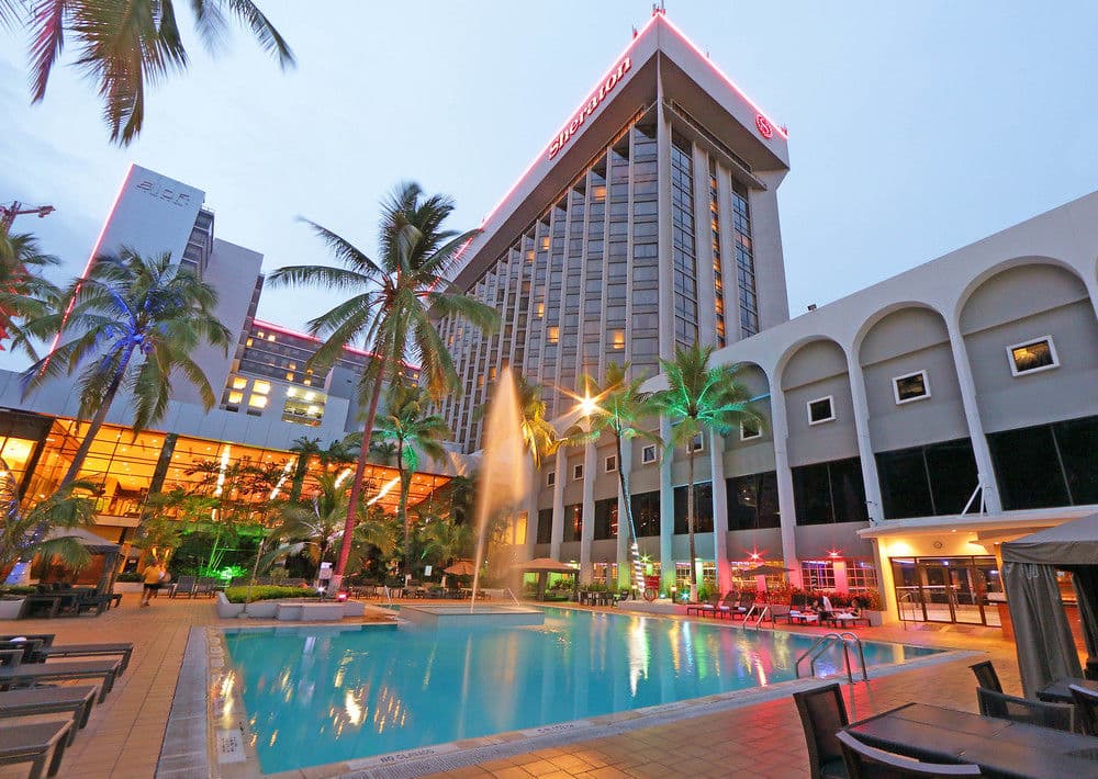 Sprawling outdoor pool terrace at Sheraton Grand Panama at sunset with illuminated fountains and palm trees.