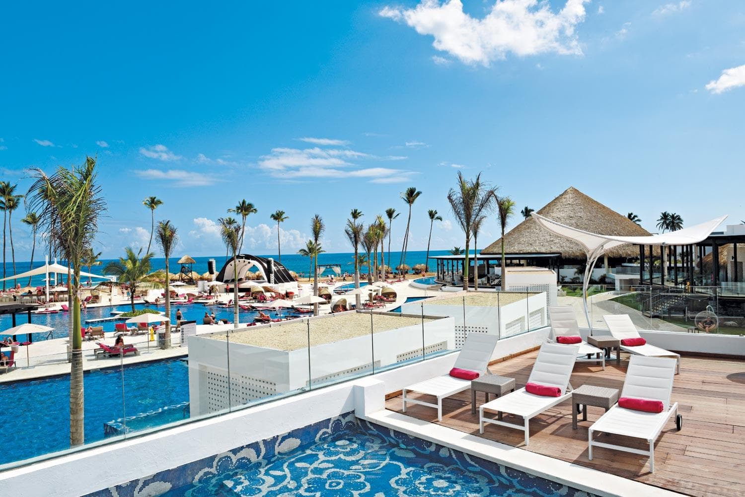 Royalton CHIC Punta Cana 的高架玻璃牆美人魚泳池,客人在其中游泳,背景是棕櫚樹。