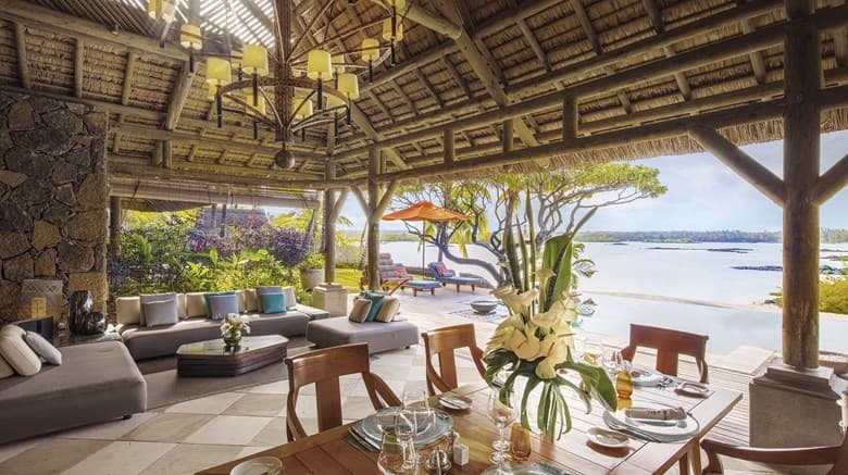 Twilight view of Le Barachois floating restaurant at Constance Prince Maurice, with lantern-lit wooden walkways over the lagoon.