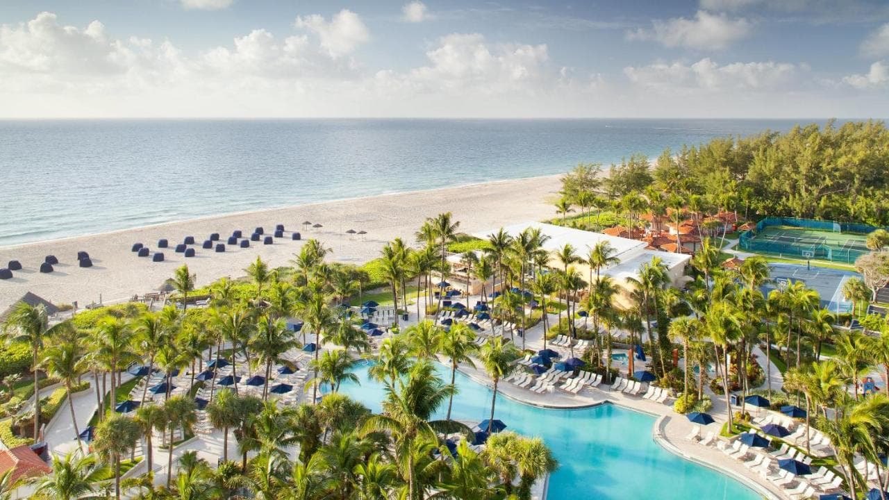 Aerial view of the Fort Lauderdale Marriott Harbor Beach Resort showing the lagoon pool and private beach at sunrise.