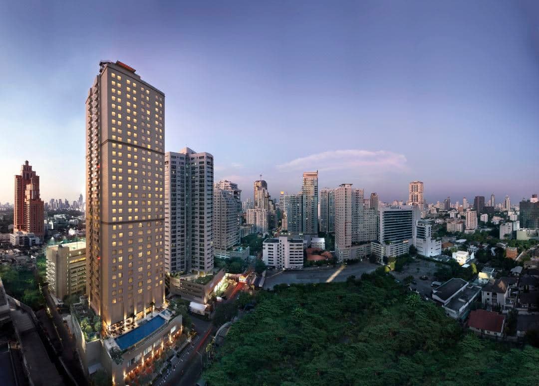 A sprawling 25-meter saltwater pool lined with tropical palm trees at Marriott Executive Apartments Sukhumvit Park, Bangkok.