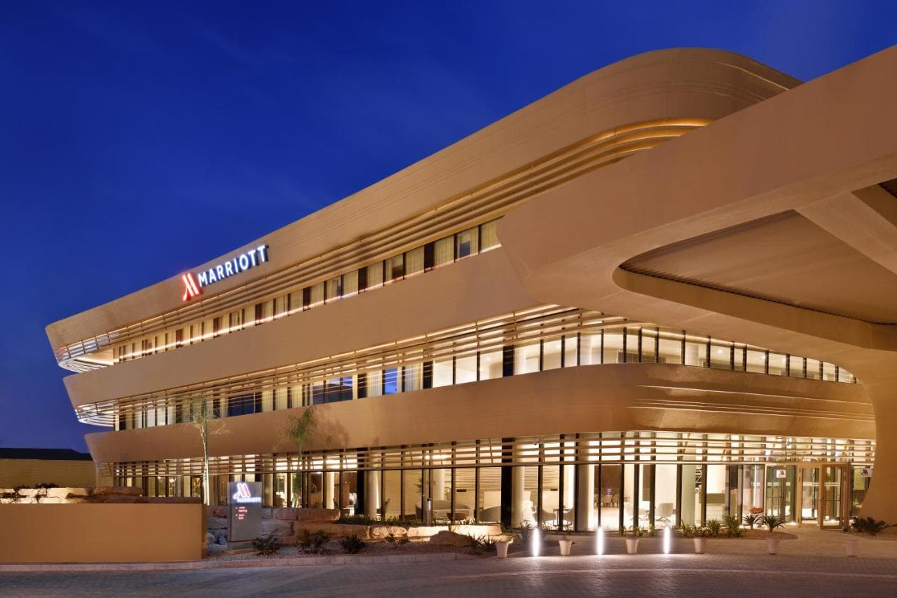The Riyadh Marriott DQ's wadi-inspired courtyard pool framed by textured sandstone walls and native palm trees.
