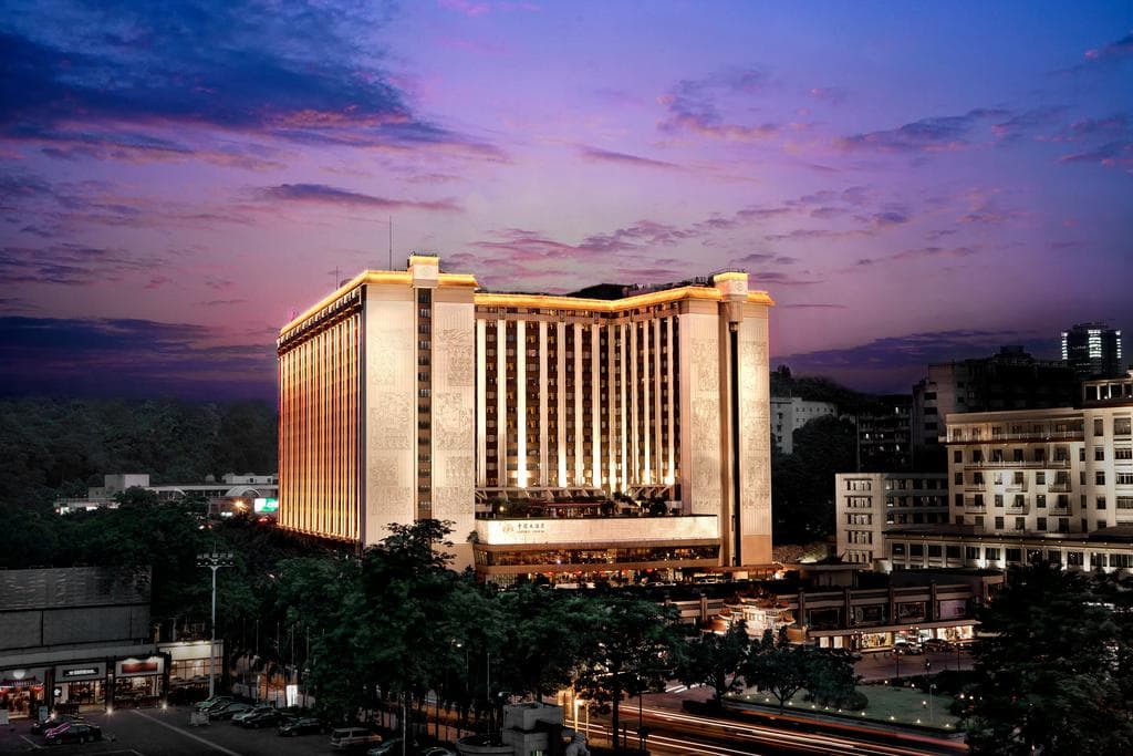 The retro white stepped facade of China Hotel Guangzhou featuring classic 1980s architecture against a blue sky.
