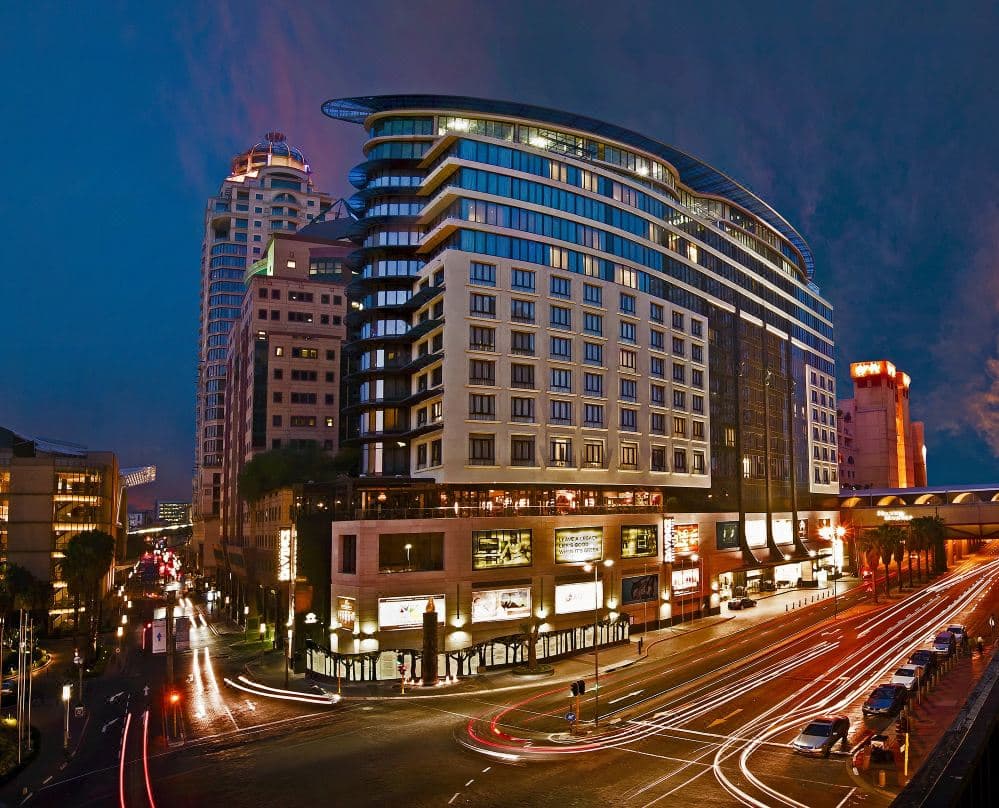 The DAVINCI Hotel heated infinity pool deck featuring a vertical living plant wall and views of the Sandton skyscrapers.
