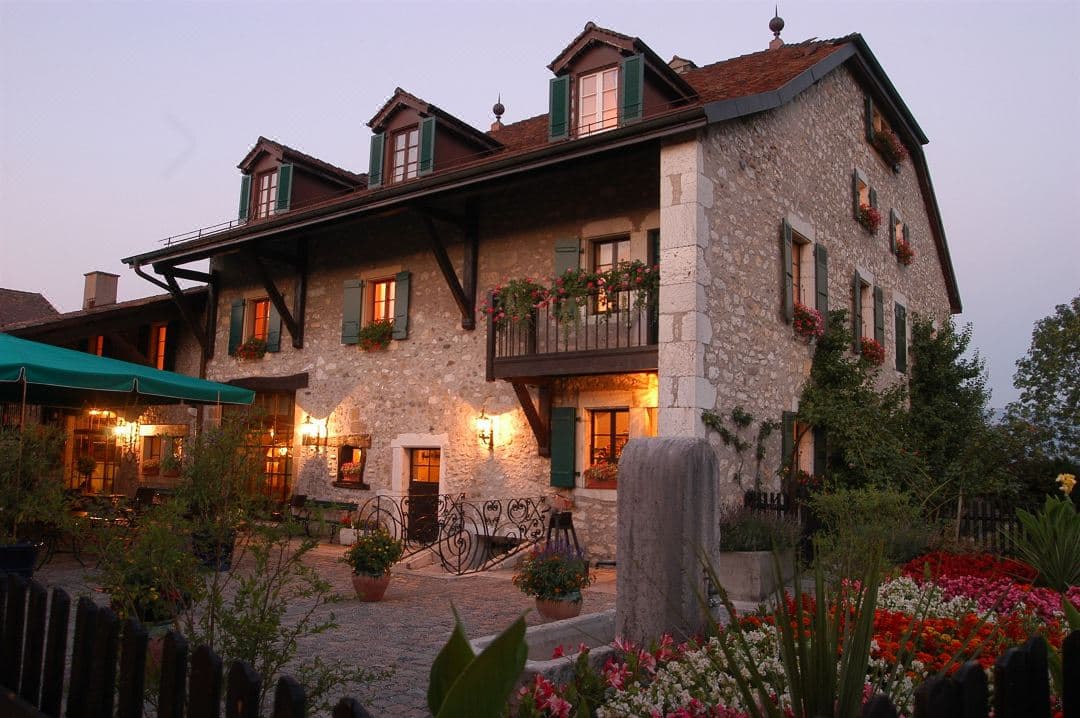 Stone facade of Domaine De Chateauvieux at sunset surrounded by Satigny vineyards.
