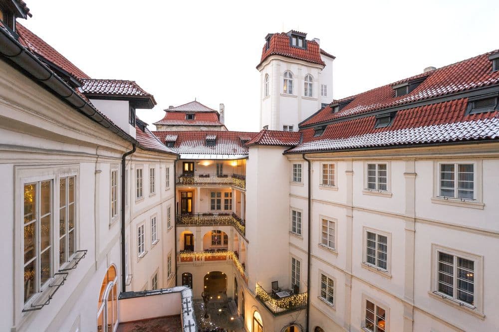 The ivy-draped private courtyard of the Iron Gate Hotel & Suites in Prague, set with tables for dining.