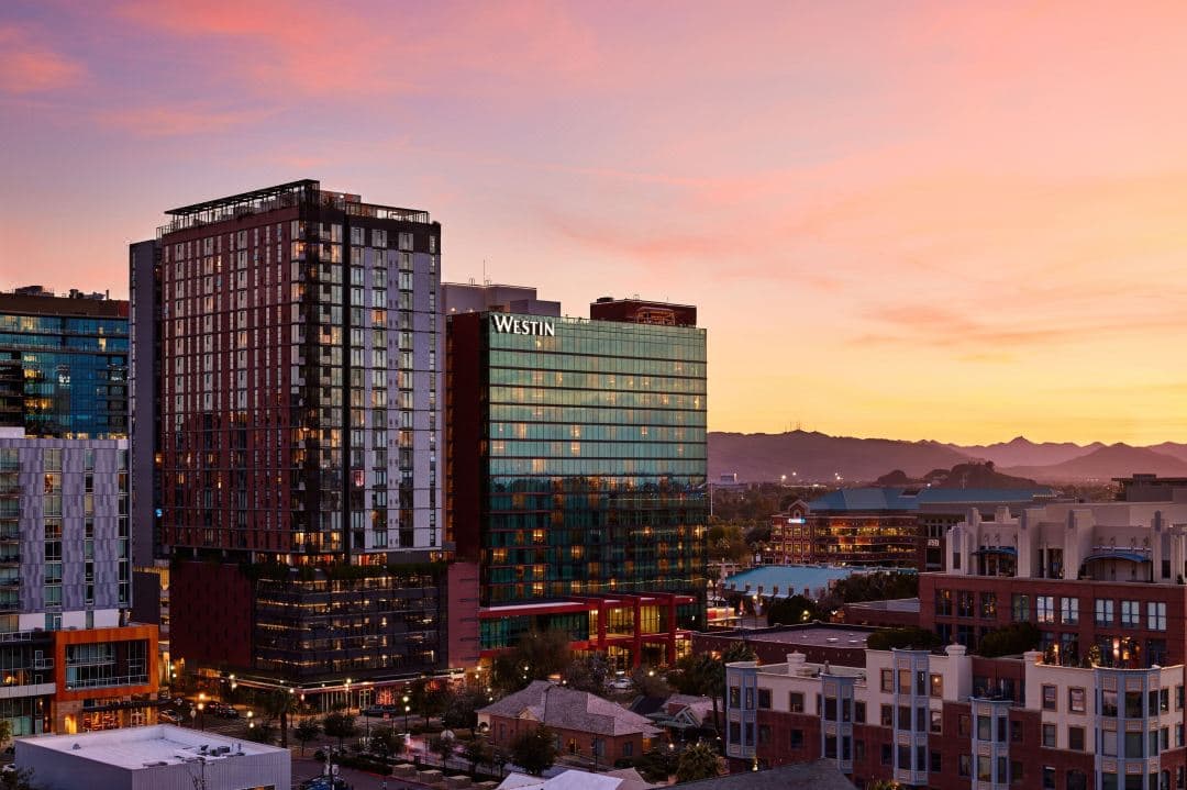 Twilight view of Skysill Rooftop Lounge featuring a backlit onyx bar and infinity pool against the Phoenix skyline.