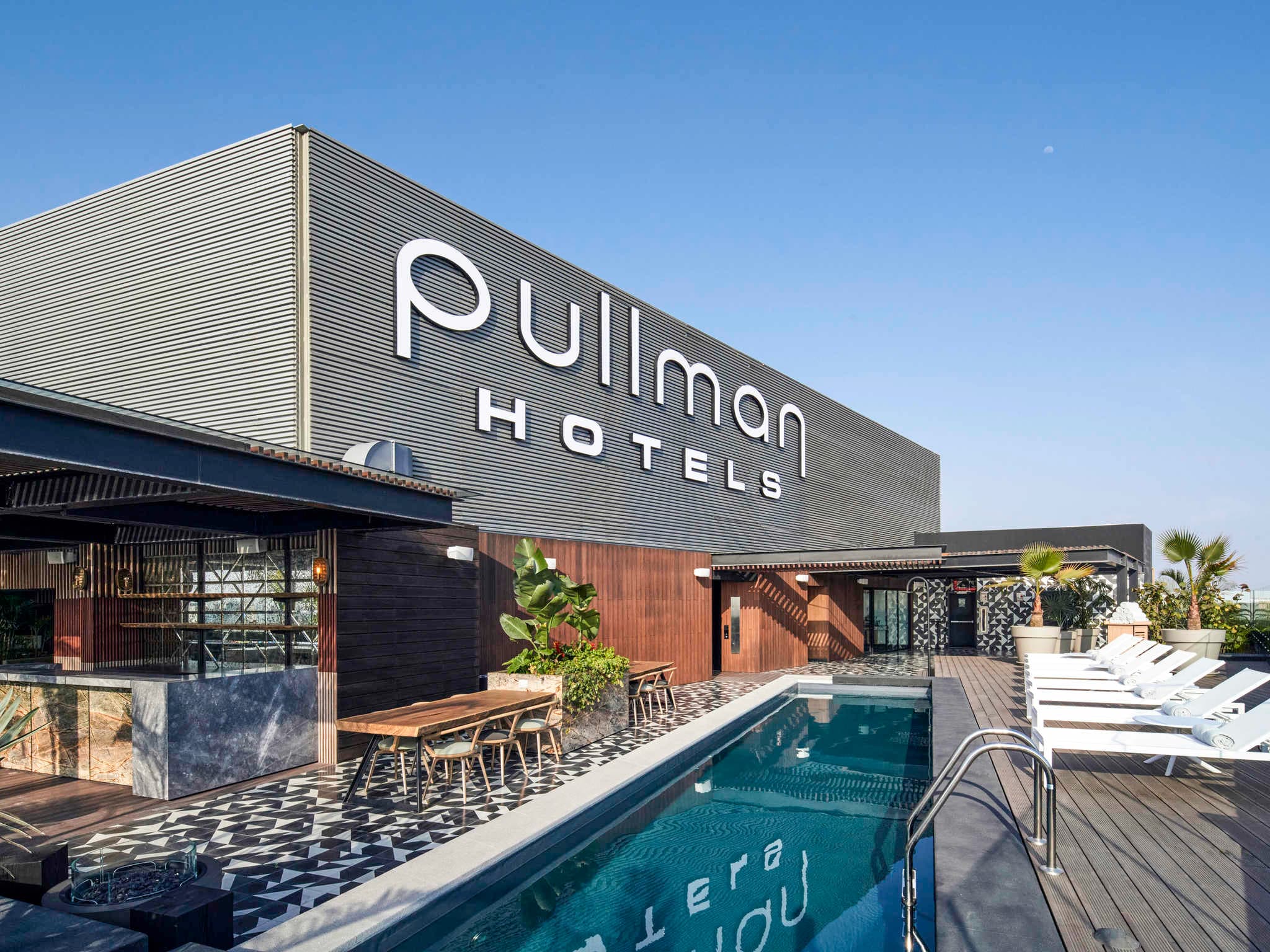 The striking black-and-white checkerboard façade of Pullman Lima Miraflores contrasting with a lush green terrace.