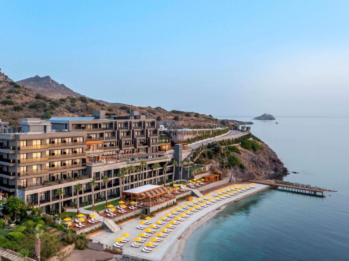 A dramatic infinity pool edge at MGallery The Bodrum suspended over a cliff, overlooking the Aegean Sea during golden hour.