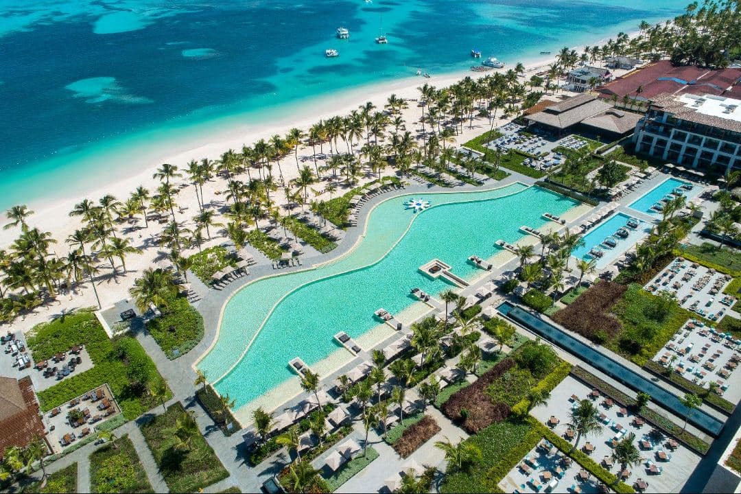 Lopesan Costa Bávaro 巨大的雙層無邊際泳池在黃昏時分與碧綠的加勒比海融為一體。