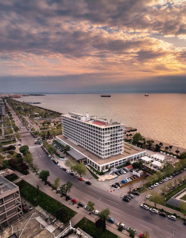 View from a Makedonia Palace suite balcony at sunset, overlooking the Thermaic Gulf and the distant White Tower of Thessaloniki.