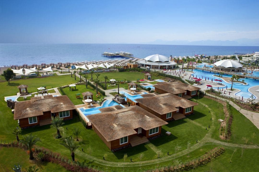 Kaya Palazzo Golf Resort의 라군 스위트 전경. 소나무 숲과 현대적인 건축물 사이로 객실과 직접 연결된 수영장이 보입니다.