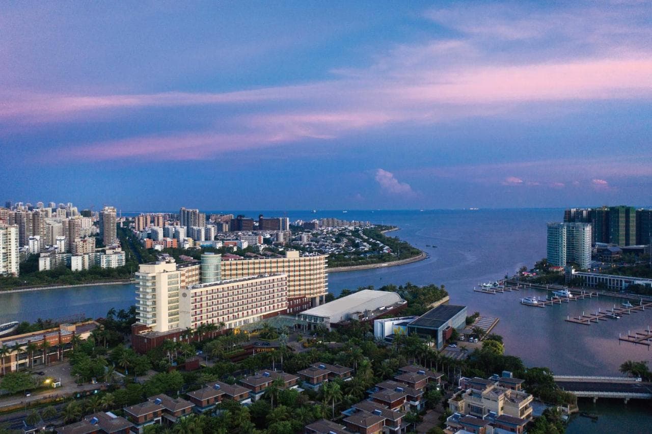 View from Pullman Haikou Executive Suite balcony overlooking the Haidian River and sea confluence at sunset.