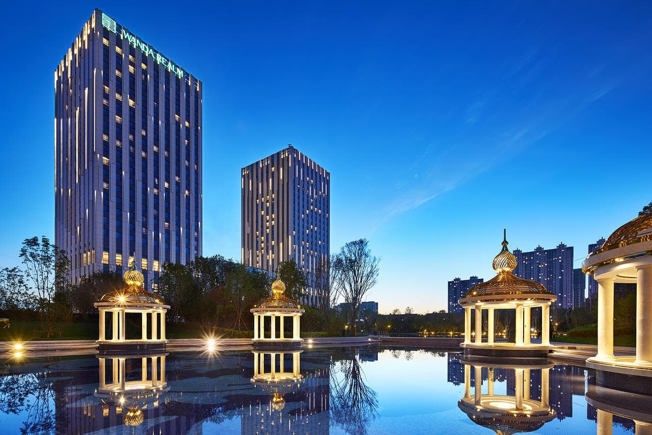 The illuminated manor-style facade of Steigenberger Hotel SUNAC Harbin glowing warmly against a twilight blue winter sky and snow-covered grounds.