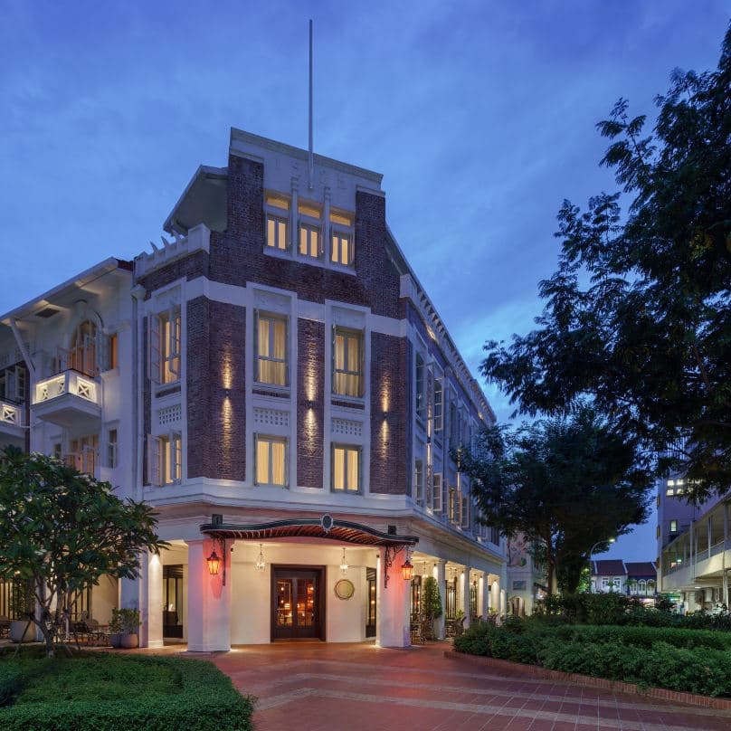 Lobby of Maxwell Reserve Singapore featuring Jacques Garcia's signature red velvet seating, intricate spiral staircase, and dark wood heritage detailing.