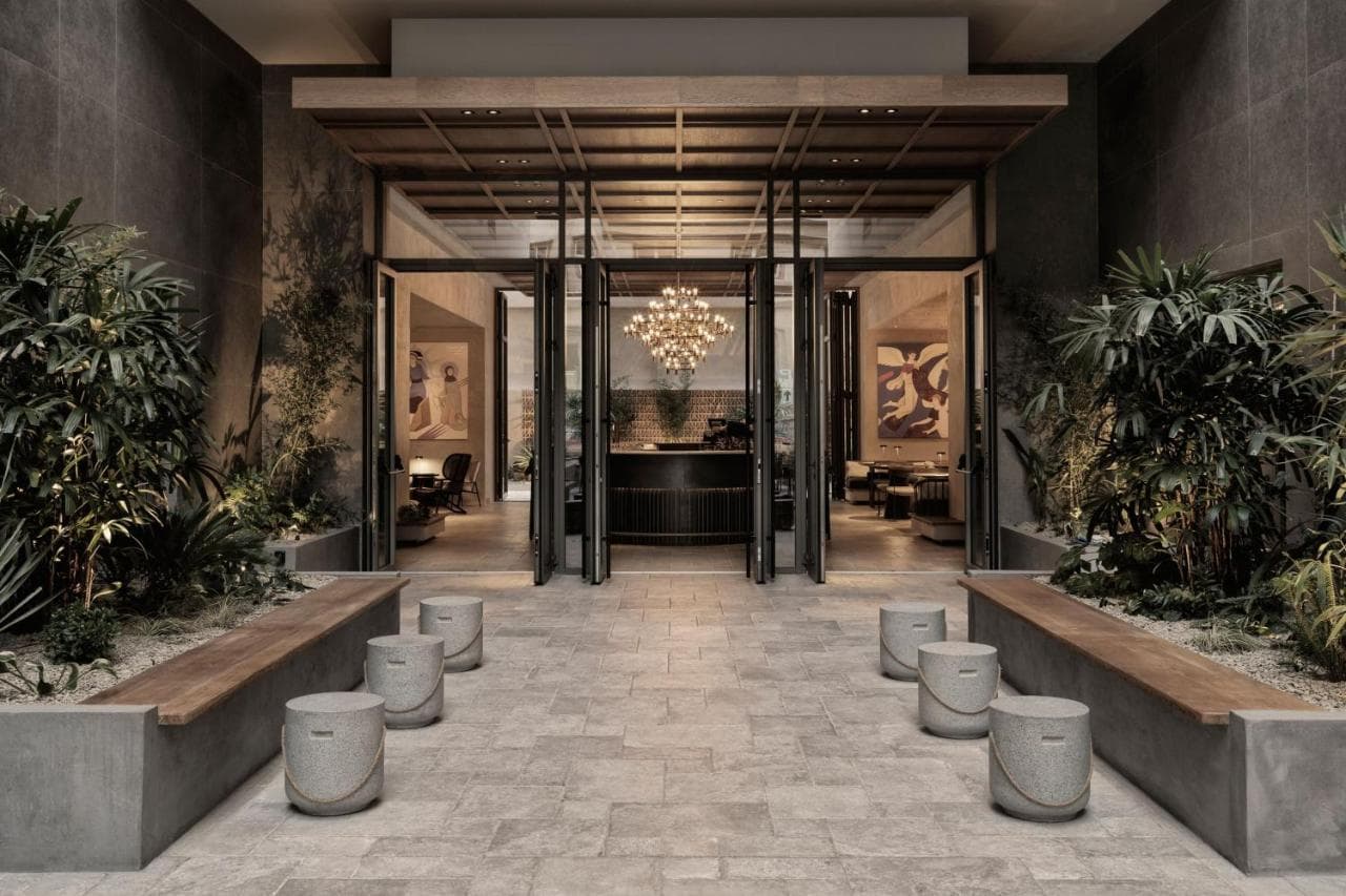 A moody, dimly lit hotel room at MonAsty Thessaloniki featuring a domed brick ceiling, arched doorways, and sophisticated neutral tones.