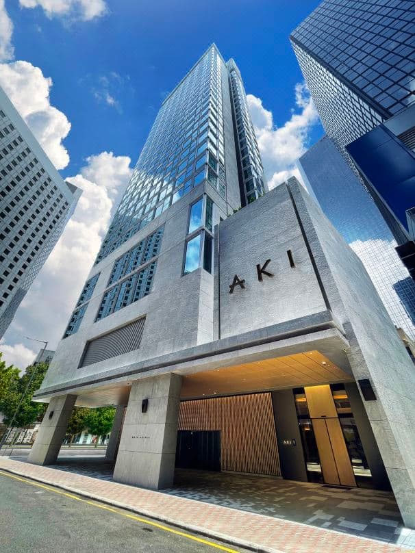 A minimalist tatami room at AKI Hong Kong featuring low-profile bedding and a panoramic 270-degree corner window overlooking the Wanchai skyline.