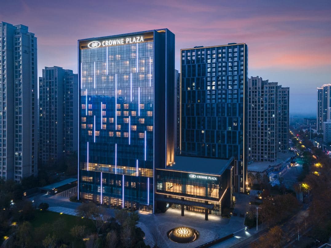 Floor-to-ceiling windows in a luxury suite at Crowne Plaza Zhengzhou High Tech Zone overlooking the city skyline at dusk.