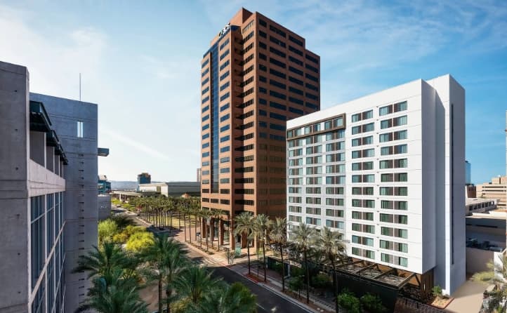 Sleek modern lobby of AC Hotel Phoenix Downtown featuring minimalist grey furniture and an outdoor patio fireplace.