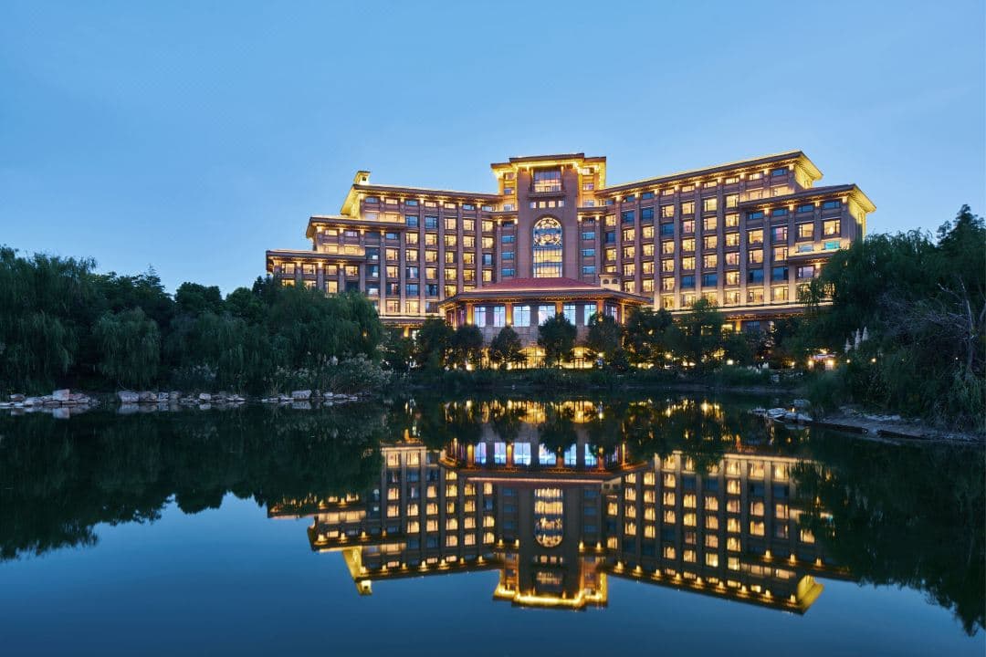 A symmetrical view of the Yuluxe Hotel Taizhou's 50-meter indoor pool with crystal clear water and lounge chairs.