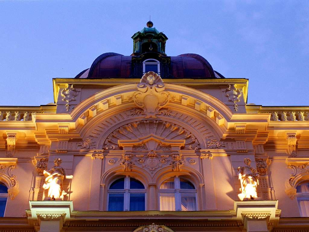 The Century Old Town Prague's grand Neo-Baroque staircase featuring wrought-iron banisters and a bust of Franz Kafka.