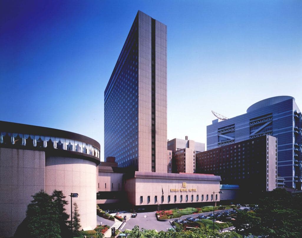 大阪麗嘉皇家酒店宏偉的大廳，紫色的「紫雲」水晶雲吊燈懸掛在綠色地毯覆蓋的橋樑上方。