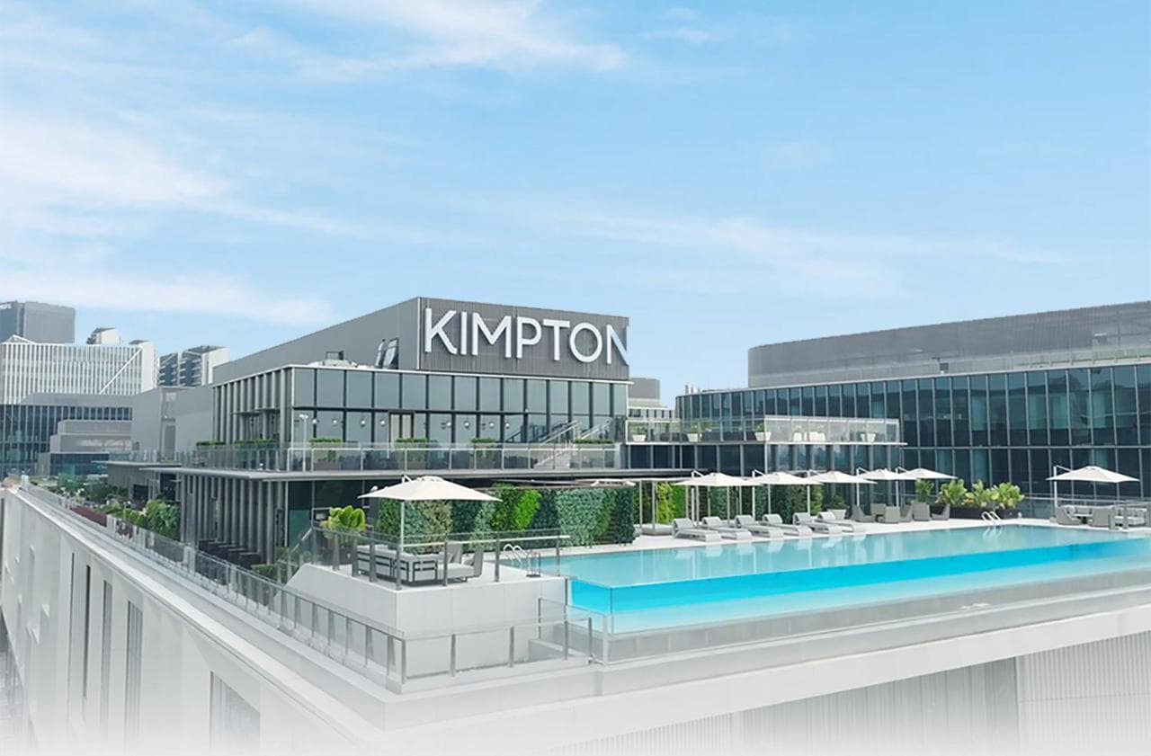 A chic, dimly lit hotel room at Kimpton Qiantan Shanghai featuring a retractable desk, floor-to-ceiling windows with skyline views, and industrial-style metal partitions.