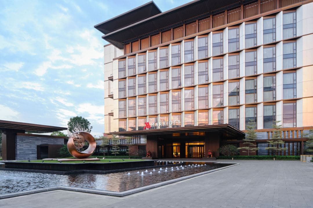A serene, glass-walled lobby lounge at Guangzhou Marriott Hotel Baiyun overlooking a lush internal courtyard garden.
