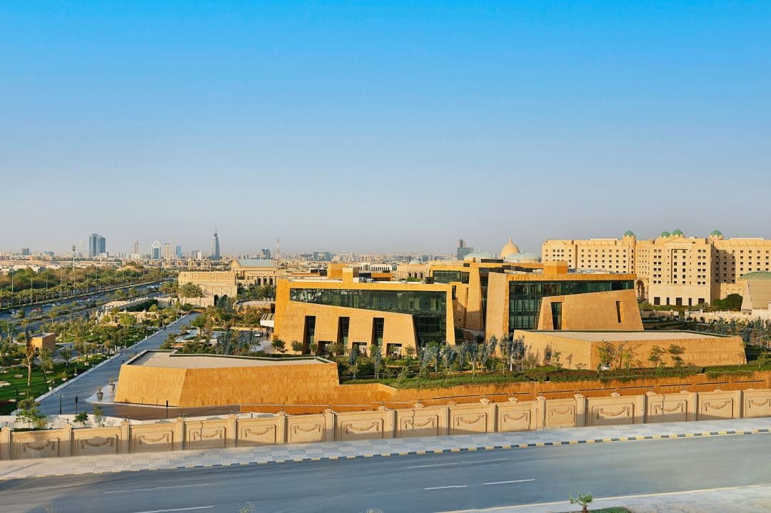 The St. Regis Riyadh exterior featuring Salmani Tuwaiq mountain stone architecture and the Stella Sky Lounge pool at twilight.