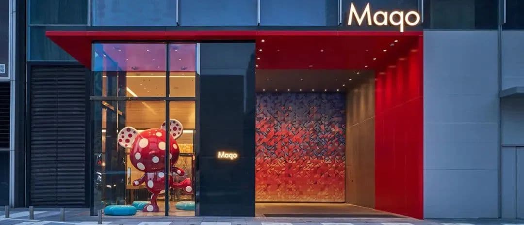 A vibrant, pop-art inspired hotel room at Maqo Changsha featuring a central island vanity, bold red and blue color blocking, and floor-to-ceiling windows overlooking the Changsha skyline.