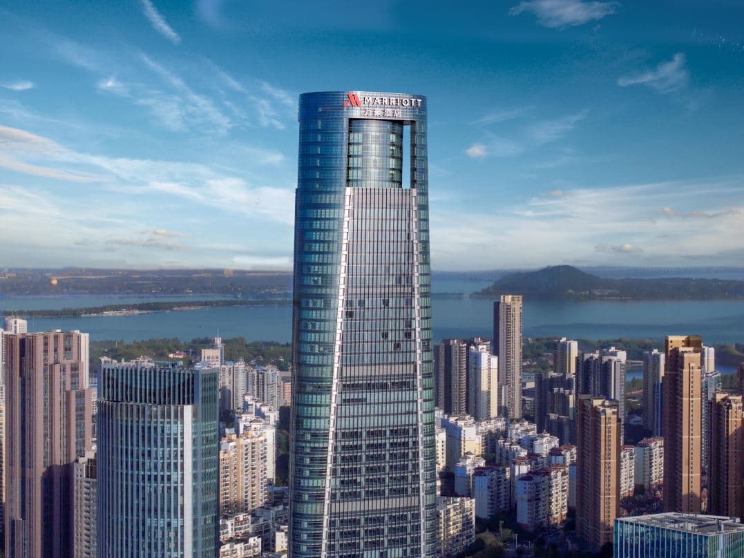 A dramatic dusk view from a high-floor room at Wuhan Marriott Hotel Wuchang, featuring floor-to-ceiling windows overlooking East Lake and the glittering city skyline.