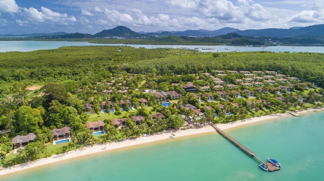 황혼 무렵 랜턴 불빛이 물에 반사되는 Barcelo Coconut Island 부두와 태국 전통 지붕의 전경.