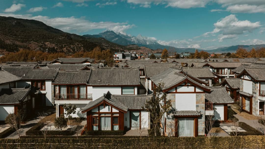 A lush courtyard at Gelle Freres Garden Hotel featuring traditional Naxi curved roofs and French-inspired manicured gardens.