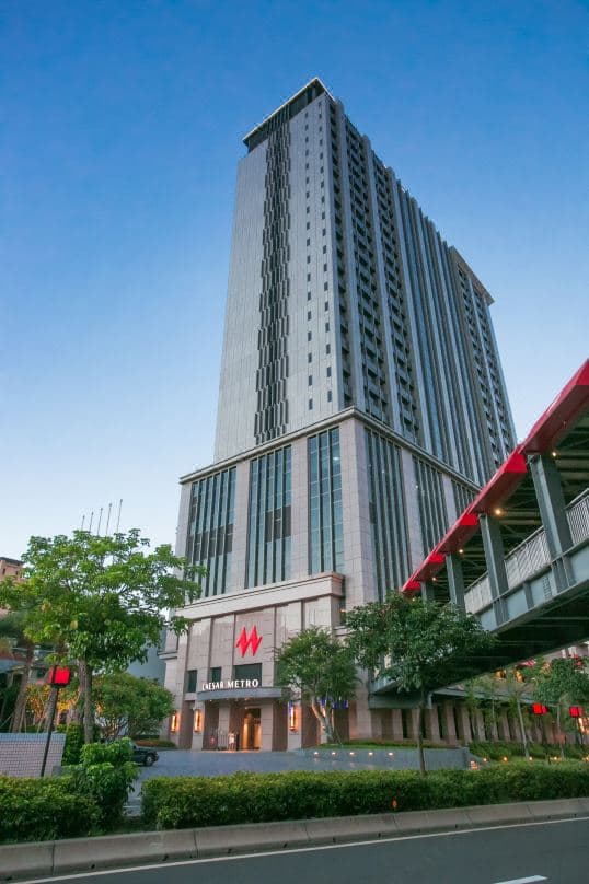 凯达大饭店宏伟的玻璃帷幕外观，耸立在万华老旧街区之上，形成强烈的古今对比。