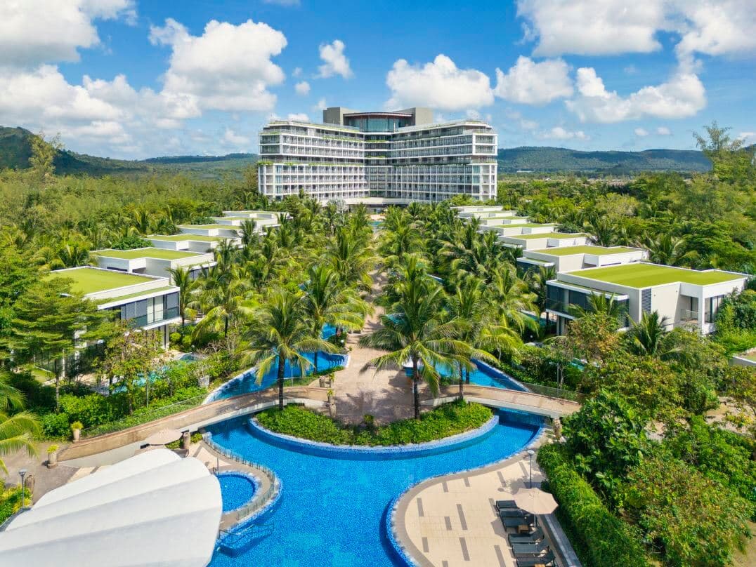 Aerial view of the 300-meter lagoon pool at Best Western Premier Sonasea leading towards the ocean during sunset.
