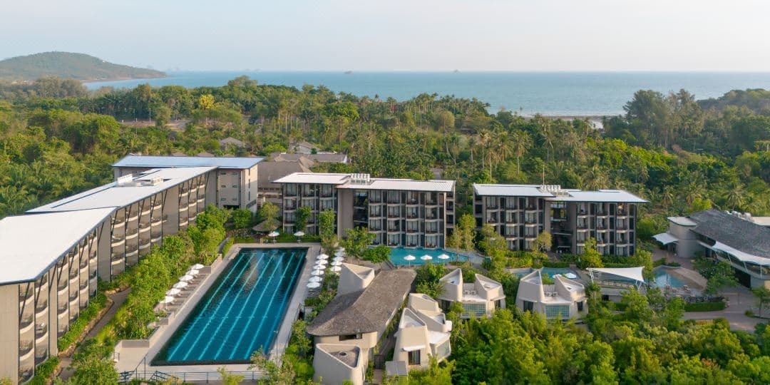The 50-meter Olympic lap pool at Varana Hotel Krabi reflecting the limestone Dragon Crest Mountain under a clear blue sky.