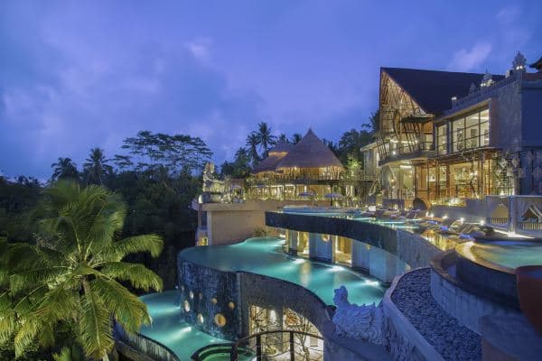 A dramatic three-tiered infinity pool at The Kayon Jungle Resort curving like rice terraces against a misty Balinese rainforest backdrop.