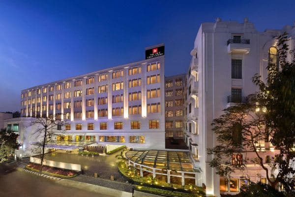 The soaring Atrium at The LaLiT Great Eastern Kolkata, featuring a modern glass facade contrasting with white Edwardian columns and iron railings.