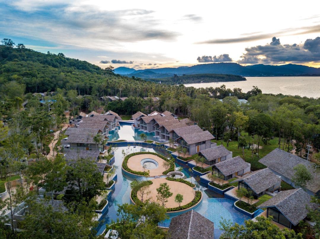 Island Escape Burasariの貝殻型インフィニティプールと茅葺き屋根のヴィラ、アンダマン海の空撮。