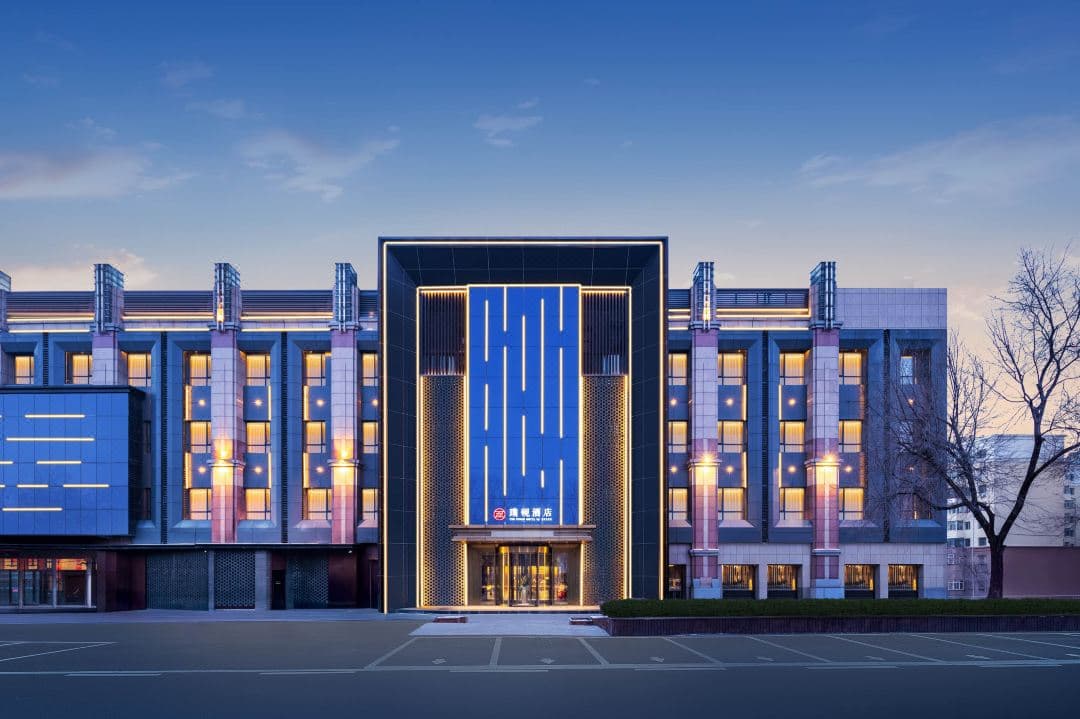 A warm, wood-paneled hotel room with floor-to-ceiling windows looking out over a frozen river and cable cars in Harbin.