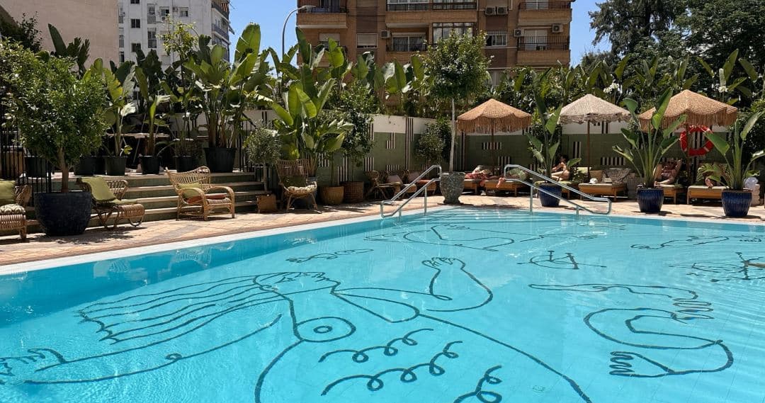 A sun-drenched pool deck with Mediterranean blue tiling and white loungers at Only YOU Hotel Sevilla.