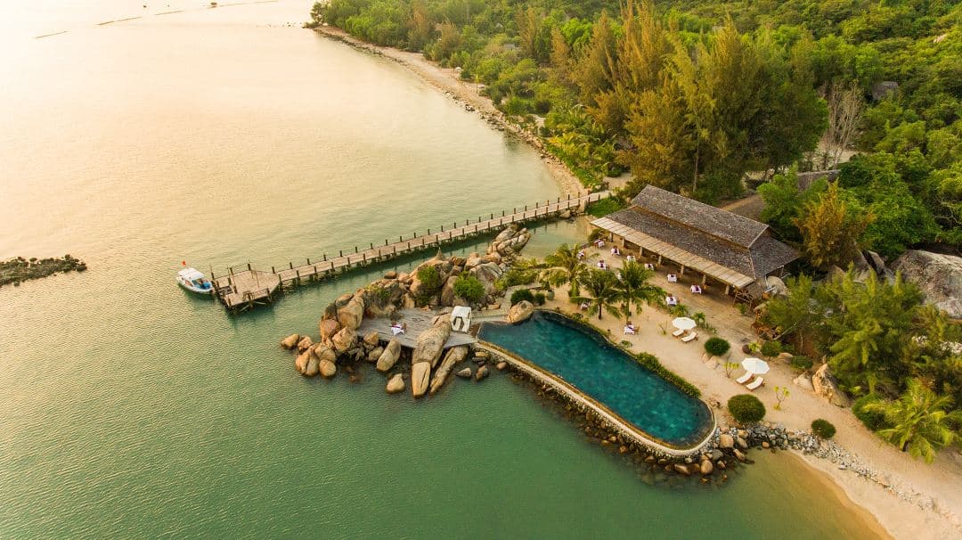 A thatched-roof Hill Rock Villa at L'Alya Ninh Van Bay with a private infinity pool suspended over the lush jungle canopy and turquoise waters.