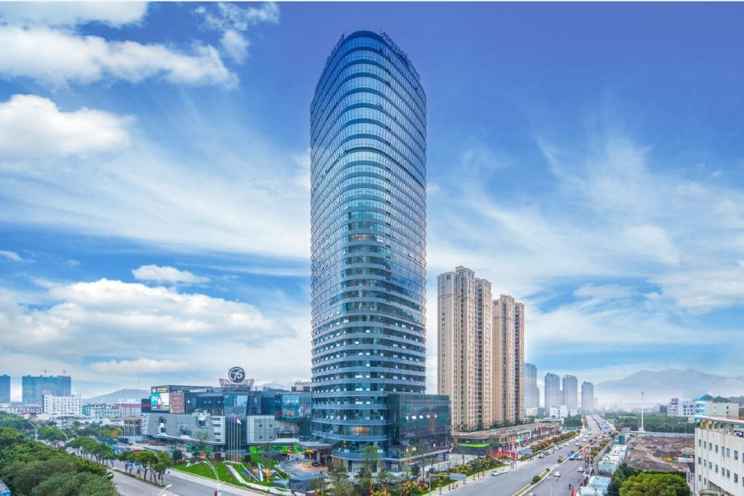 A serene, heated indoor pool at Howard Johnson Plaza Ningbo with floor-to-ceiling windows overlooking the city skyline at twilight.