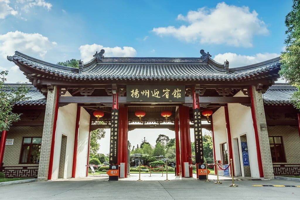 揚州迎宾館的古典亭台樓閣在瘦西湖的晨霧中倒影清晰，柳絲輕拂。