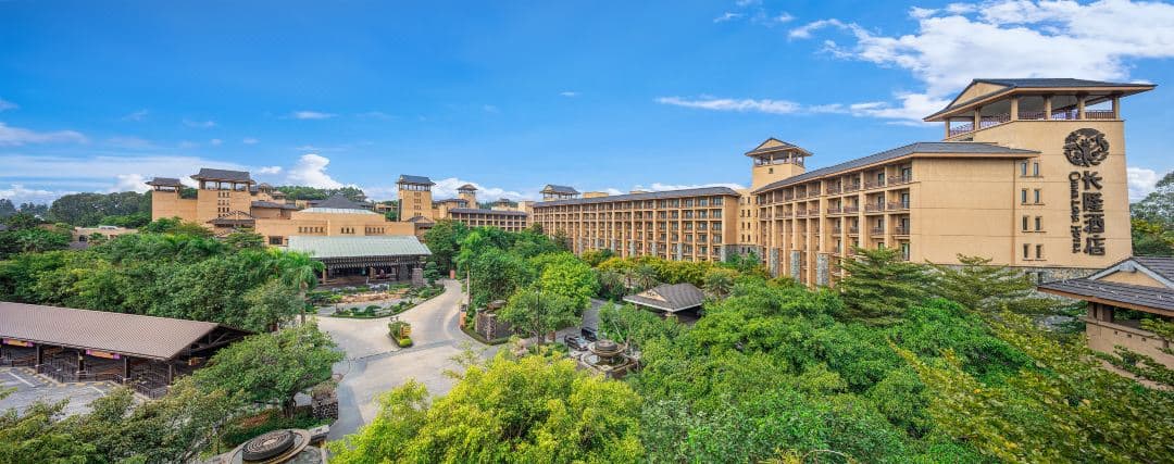View of the White Tiger Restaurant atrium at Chimelong Hotel Guangzhou, featuring floor-to-ceiling glass windows with live white tigers roaming outside.