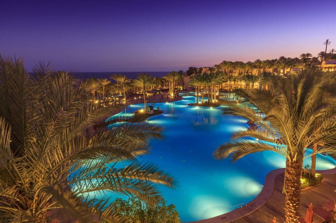 Grand Rotana Resort huge lagoon pool winding through palm gardens towards the Red Sea with Tiran Island in the distance.