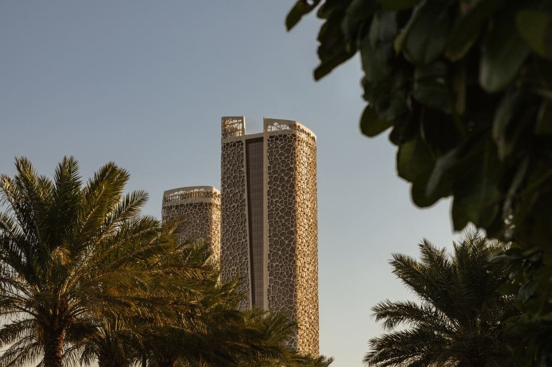Rosewood Doha's coral-inspired facade glowing at twilight, framing the Lusail Marina.